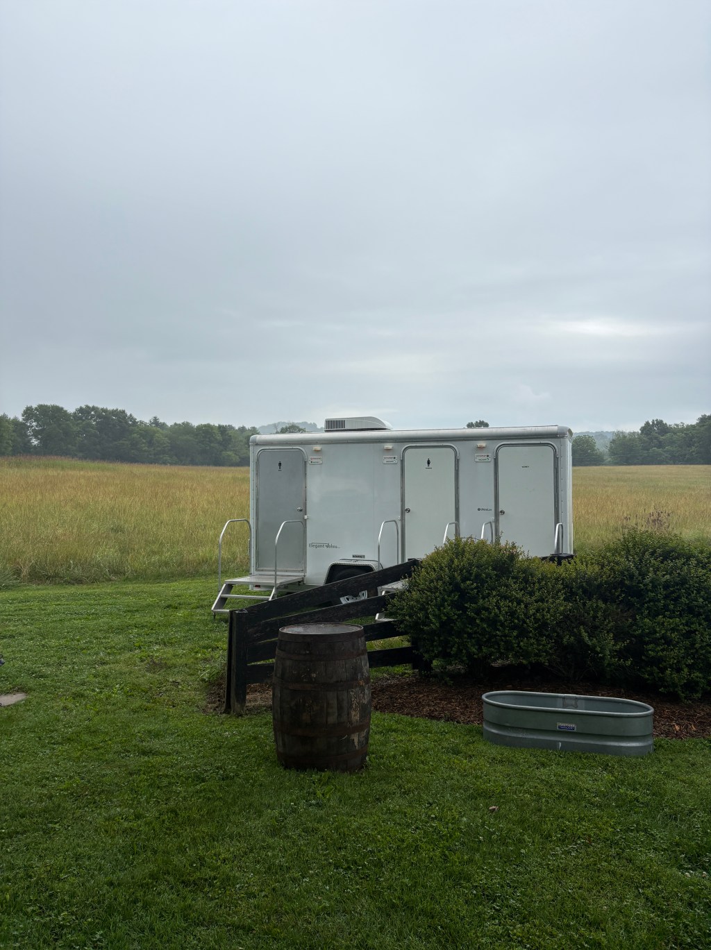 Luxury restroom trailer at night with floral planters and lit entry steps
